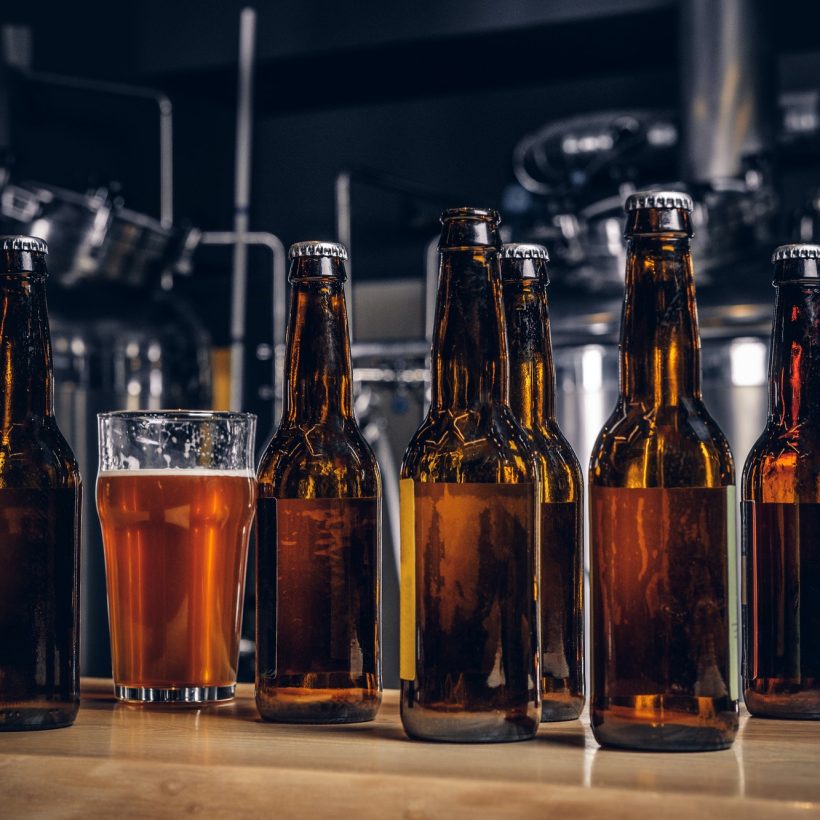 bottles-and-glass-of-craft-beer-on-wooden-bar-counter-at-the-indie-brewery-.jpg